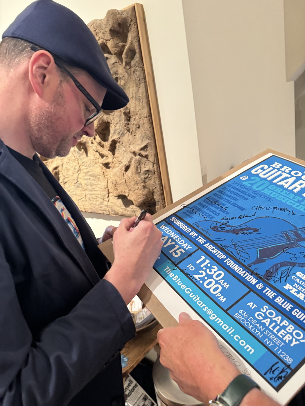 An attendee signing a blue Brooklyn Guitar Feast event sheet.